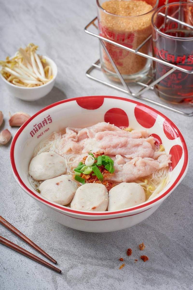 ก๋วยเตี๋ยวน้ำใสเส้นหมี่ หมูสไลด์ และลูกชิ้น ในชามลายจุดแดงของร้าน