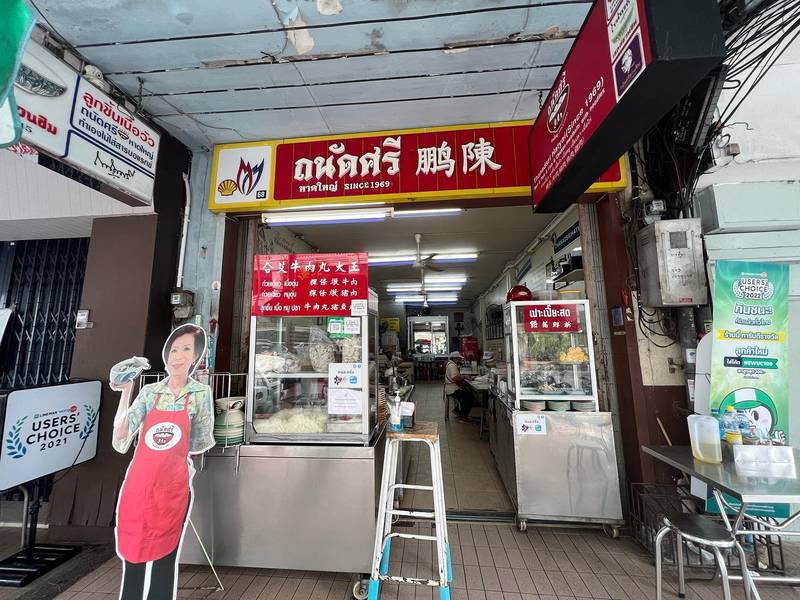 หน้าร้านถนัดศรีบนถนนธรรมนูญวิถี หาดใหญ่ ป้ายแดงอักษรไทยและจีน